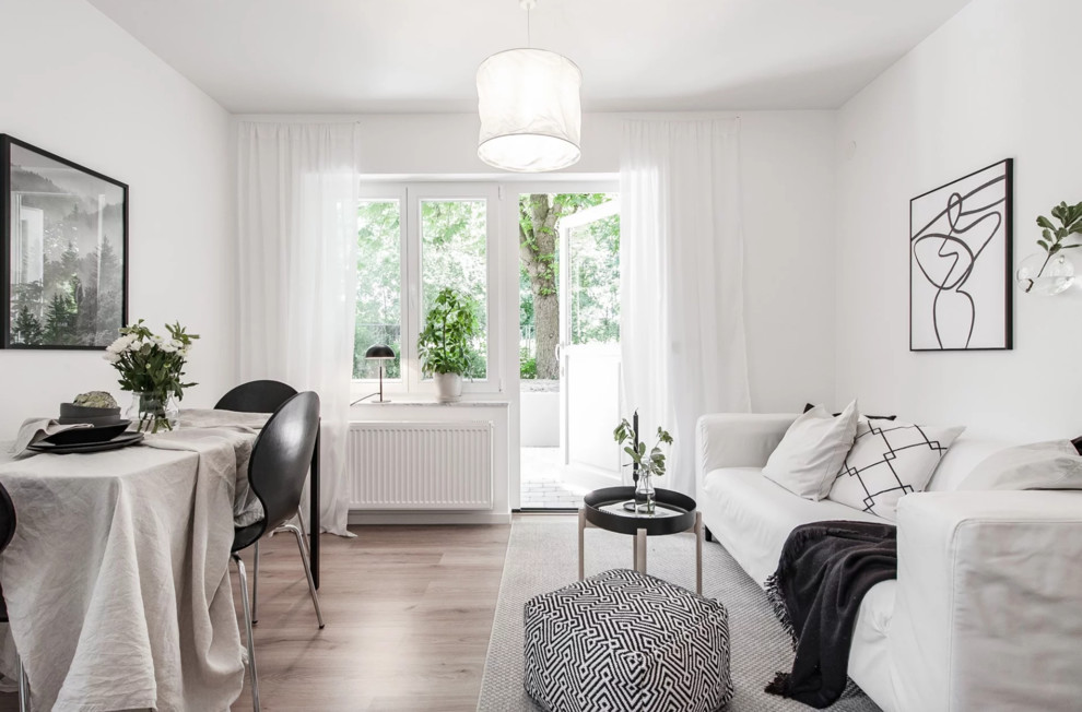 Bild på ett litet minimalistiskt allrum med öppen planlösning, med vita väggar, ljust trägolv och beiget golv
