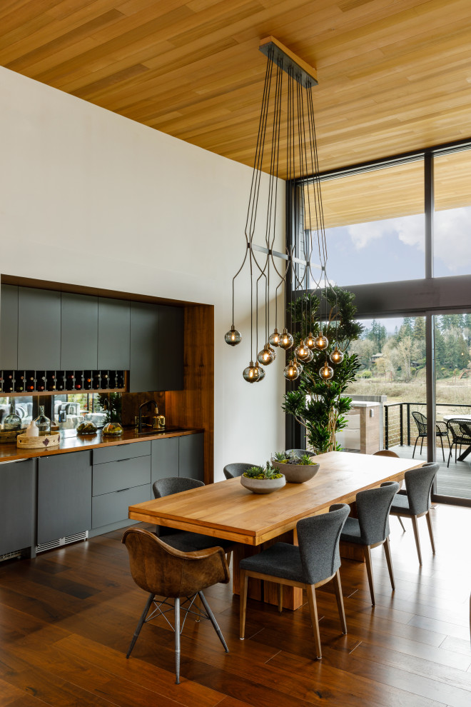 This is an example of a midcentury open plan dining in Portland with white walls, medium hardwood floors, brown floor and wood.