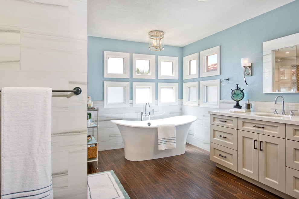 Inspiration for a large transitional master bathroom in San Diego with recessed-panel cabinets, beige cabinets, a freestanding tub, a one-piece toilet, white tile, porcelain tile, blue walls, porcelain floors, an undermount sink, engineered quartz benchtops, brown floor and an open shower.