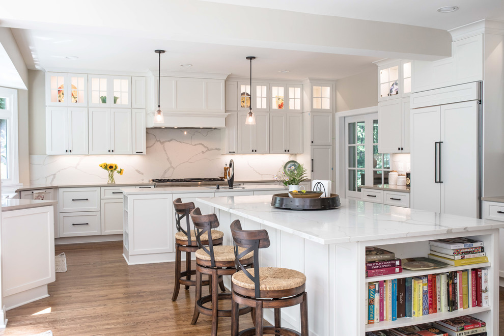 Design ideas for a transitional u-shaped eat-in kitchen in DC Metro with an undermount sink, shaker cabinets, white cabinets, white splashback, panelled appliances, light hardwood floors, multiple islands and brown floor.