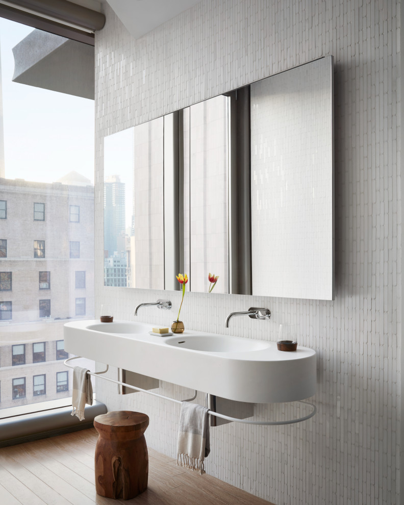 Esempio di una stanza da bagno design con piastrelle bianche, pavimento in legno massello medio, lavabo sospeso, pavimento marrone, due lavabi e mobile bagno sospeso