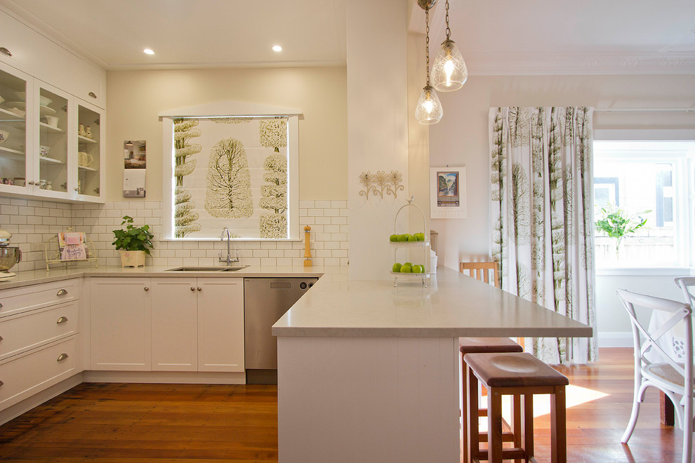 Design ideas for a small traditional u-shaped eat-in kitchen in Wellington with an undermount sink, shaker cabinets, white cabinets, granite benchtops, white splashback, subway tile splashback, stainless steel appliances, medium hardwood floors and a peninsula.