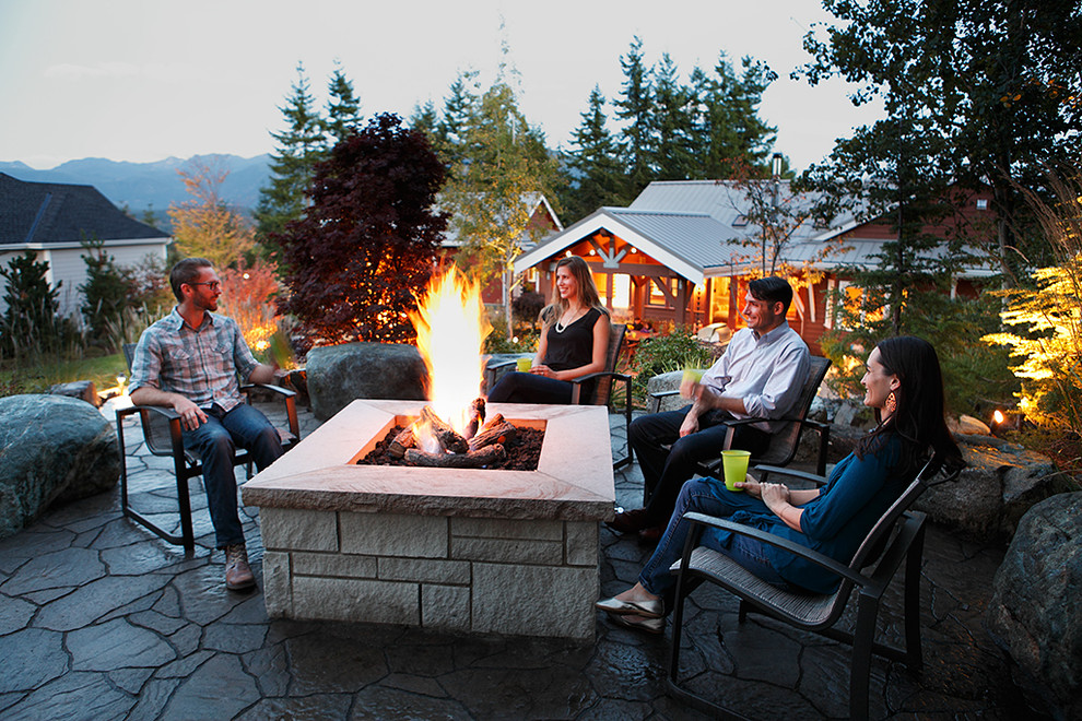 This is an example of a mid-sized country backyard patio in Seattle with a fire feature, concrete pavers and no cover.