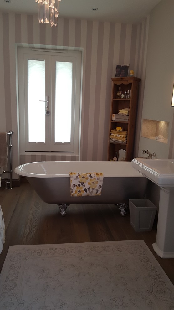 This is an example of a large traditional family bathroom in Other with freestanding cabinets, a freestanding bath, an alcove shower, a wall mounted toilet, grey tiles, stone tiles, grey walls, medium hardwood flooring, a pedestal sink, marble worktops, brown floors and a hinged door.