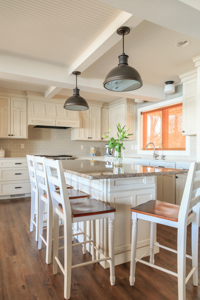 Transitional l-shaped vinyl floor open concept kitchen photo in Minneapolis with an undermount sink, raised-panel cabinets, white cabinets, quartz countertops, beige backsplash, ceramic backsplash, paneled appliances and an island