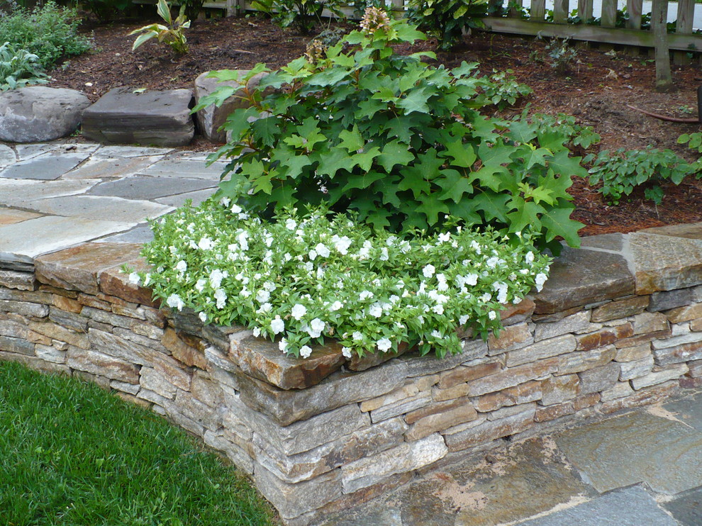 This is an example of a mid-sized rustic backyard stone retaining wall landscape in Baltimore.