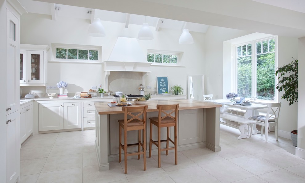 This is an example of an expansive traditional l-shaped open plan kitchen in Dublin with an integrated sink, beaded inset cabinets, quartzite benchtops, stone slab splashback, stainless steel appliances, with island and white cabinets.