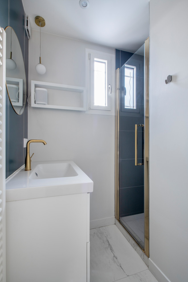 This is an example of a small modern shower room bathroom in Paris with flat-panel cabinets, white cabinets, a built-in shower, blue tiles, ceramic tiles, white walls, marble flooring, a console sink, solid surface worktops, white floors, a hinged door, white worktops, a single sink and a freestanding vanity unit.