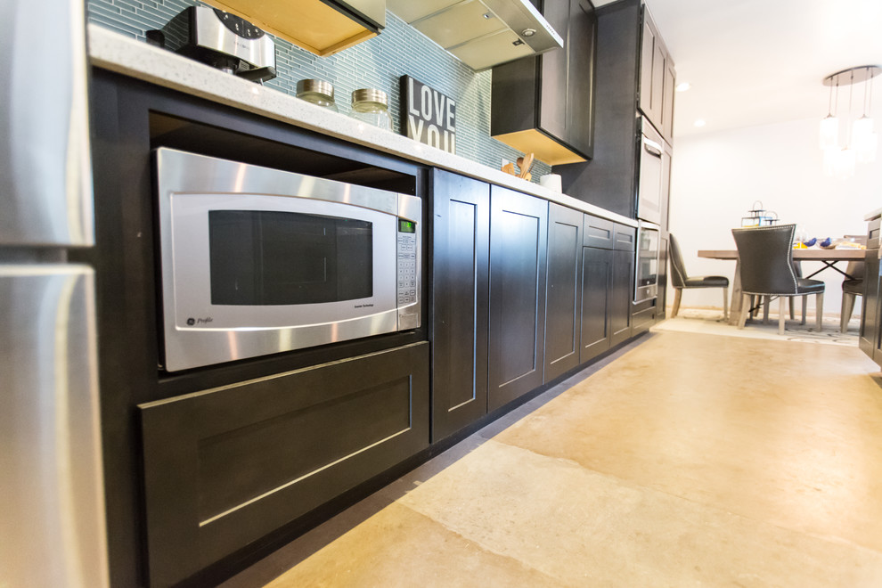 Mid-sized mountain style single-wall concrete floor and gray floor open concept kitchen photo in Phoenix with dark wood cabinets, blue backsplash, stainless steel appliances, an island, an undermount sink, shaker cabinets, quartzite countertops and glass tile backsplash