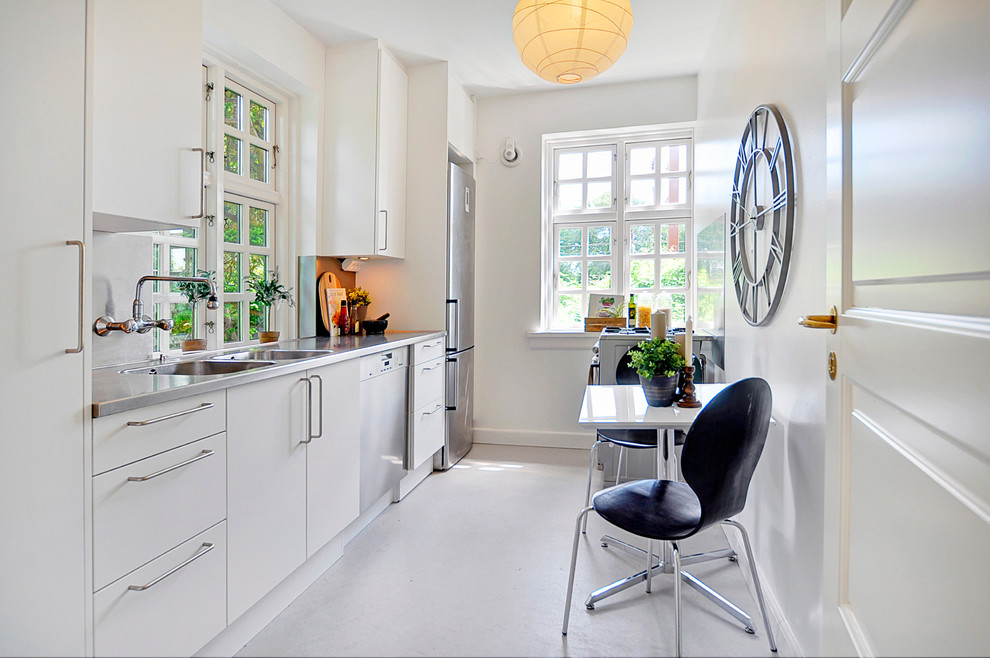 Mid-sized scandinavian single-wall separate kitchen in Copenhagen with a double-bowl sink, flat-panel cabinets, white cabinets, stainless steel benchtops, stainless steel appliances, no island and linoleum floors.