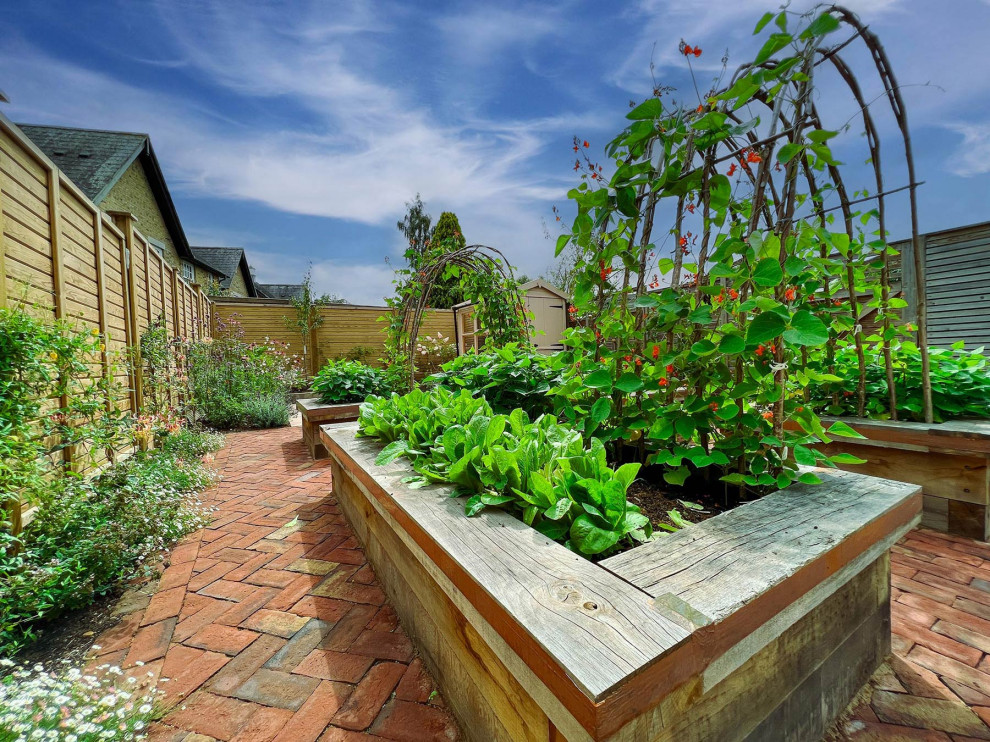 Cette image montre un jardin victorien de taille moyenne et l'été avec une exposition ensoleillée et une clôture en bois.