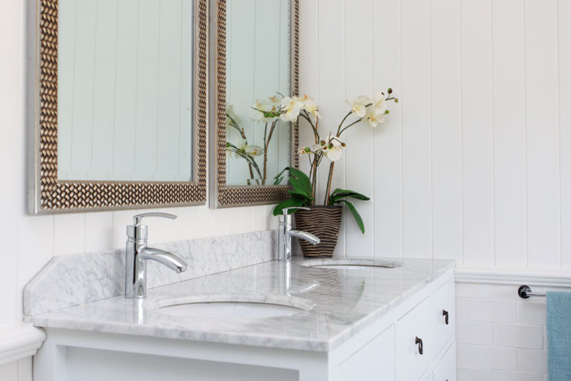 Photo of a traditional bathroom in Brisbane with recessed-panel cabinets, white cabinets, an undermount sink and marble benchtops.