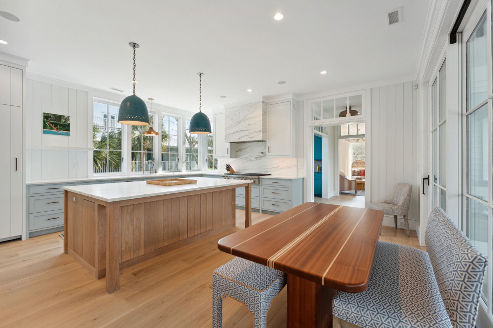 Foto de cocina marinera grande con encimera de mármol, electrodomésticos con paneles, suelo de madera clara y encimeras blancas