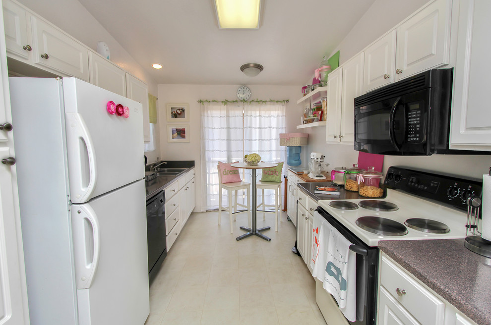 Small beach style galley separate kitchen in Orange County with white cabinets.