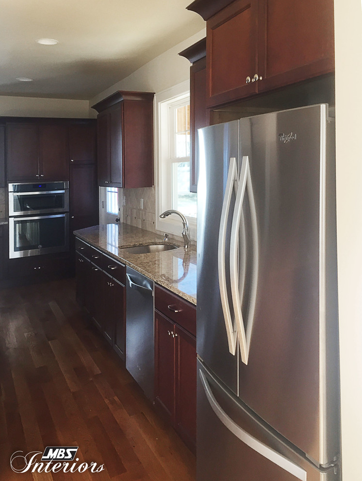 Example of a large transitional medium tone wood floor eat-in kitchen design in Cincinnati with an undermount sink, recessed-panel cabinets, dark wood cabinets, quartz countertops, beige backsplash, stone tile backsplash, stainless steel appliances and an island