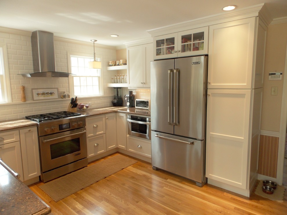 Small transitional u-shaped medium tone wood floor eat-in kitchen photo in Boston with an undermount sink, shaker cabinets, white cabinets, solid surface countertops, white backsplash, ceramic backsplash, stainless steel appliances and beige walls