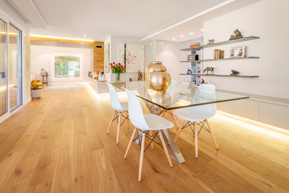 Large contemporary separate dining room in Madrid with white walls, medium hardwood floors and no fireplace.