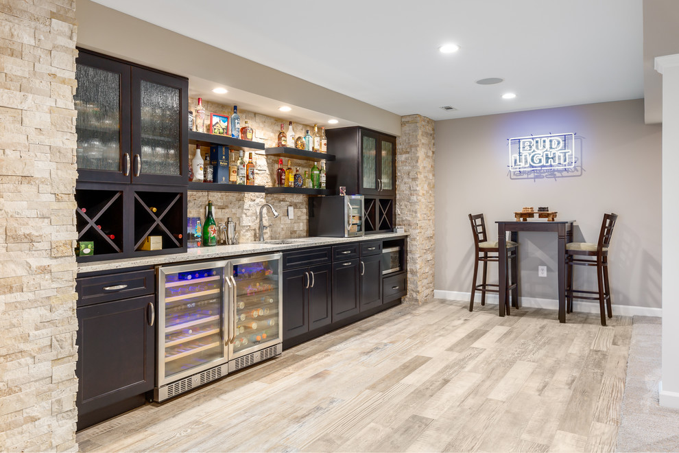 Design ideas for a large contemporary single-wall seated home bar in DC Metro with an undermount sink, shaker cabinets, dark wood cabinets, granite benchtops, brown splashback, travertine splashback, porcelain floors, beige floor and grey benchtop.