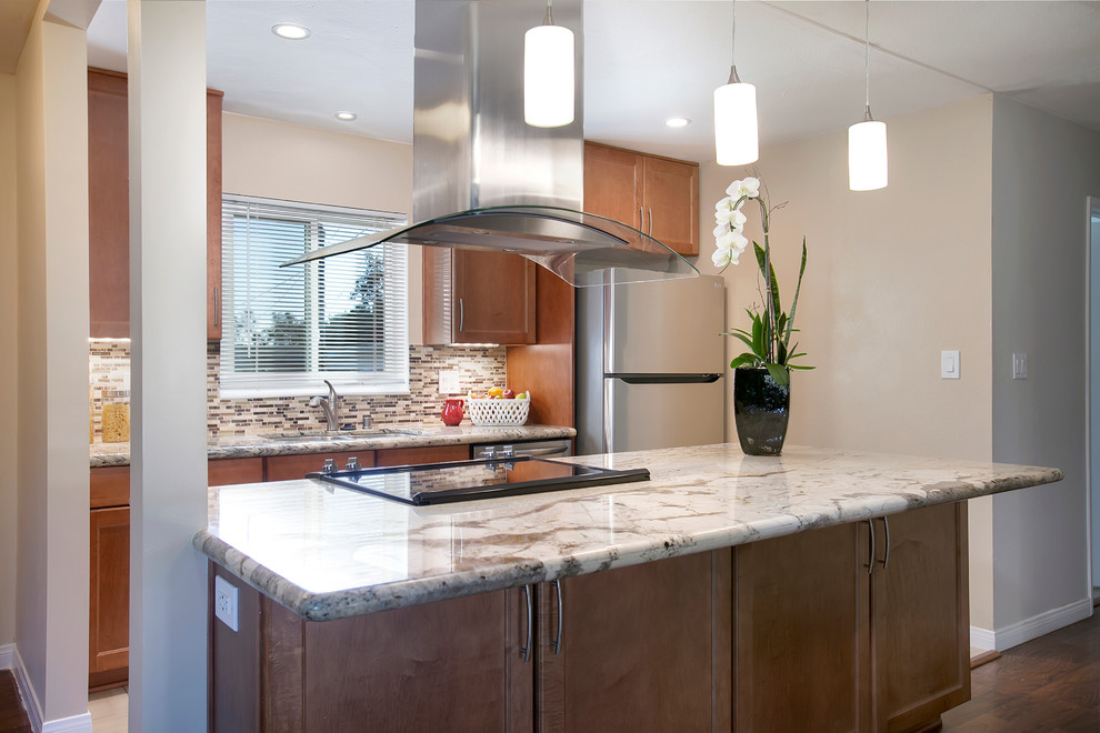 Mid-sized modern galley eat-in kitchen in San Diego with an undermount sink, recessed-panel cabinets, medium wood cabinets, granite benchtops, beige splashback, glass sheet splashback, stainless steel appliances, porcelain floors and with island.