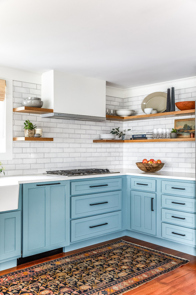 Mid-sized country kitchen in Portland Maine with shaker cabinets, blue cabinets, white splashback, brick splashback, medium hardwood floors, no island, white benchtop, a farmhouse sink and brown floor.