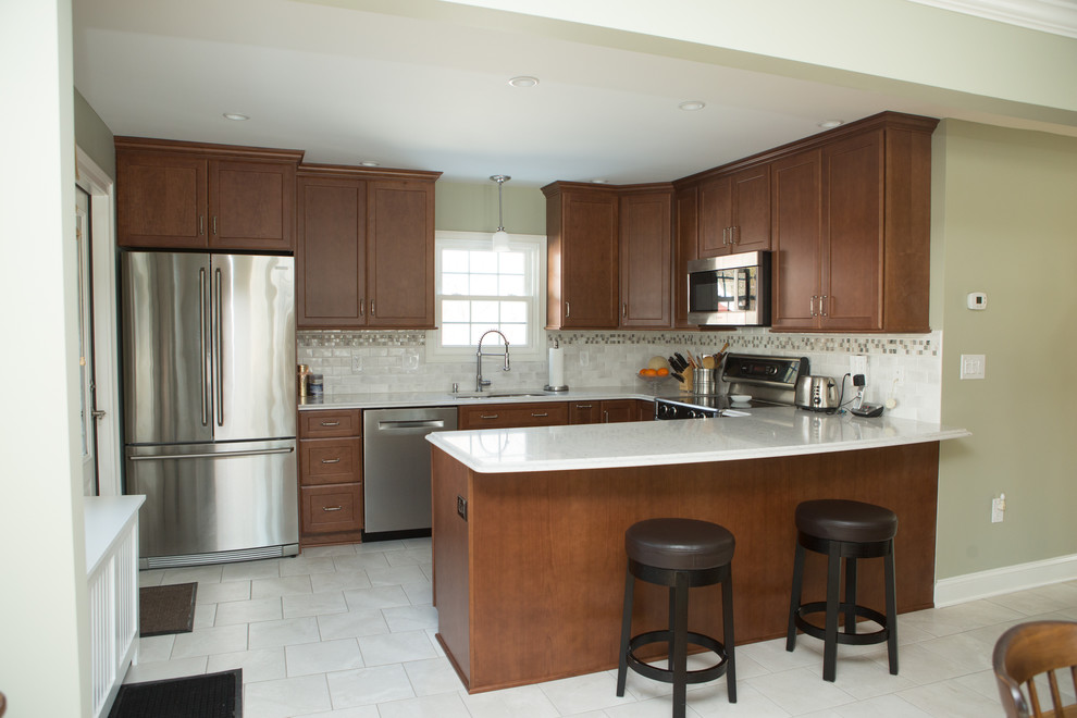 Inspiration for a mid-sized transitional l-shaped white floor and ceramic tile eat-in kitchen remodel with an undermount sink, quartz countertops, white backsplash, porcelain backsplash, stainless steel appliances, white countertops, shaker cabinets, medium tone wood cabinets and a peninsula