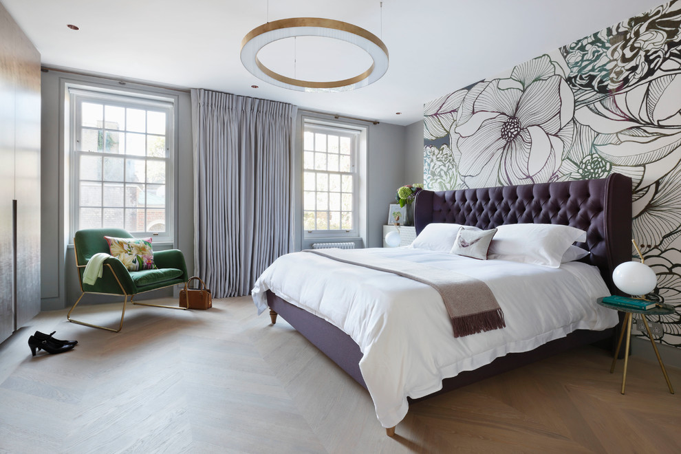 Mid-sized transitional master bedroom in London with light hardwood floors, beige floor and multi-coloured walls.