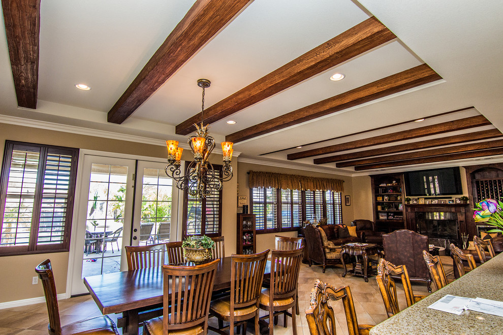 This is an example of a large traditional dining room in Orange County with beige walls, travertine floors, a standard fireplace and a wood fireplace surround.
