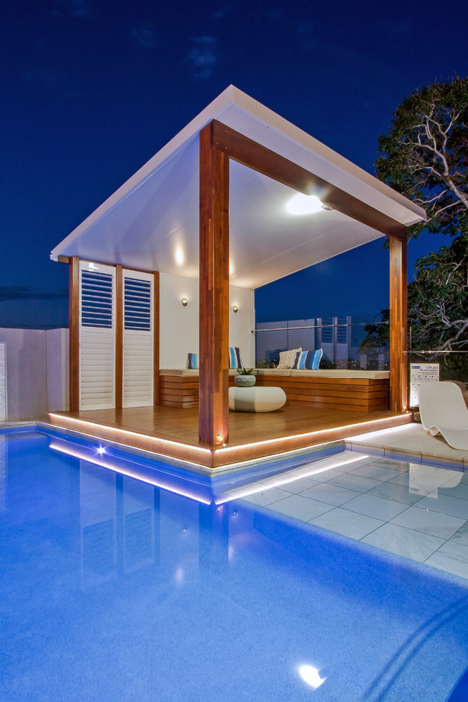 Mid-sized modern backyard custom-shaped aboveground pool in Brisbane with a pool house and natural stone pavers.