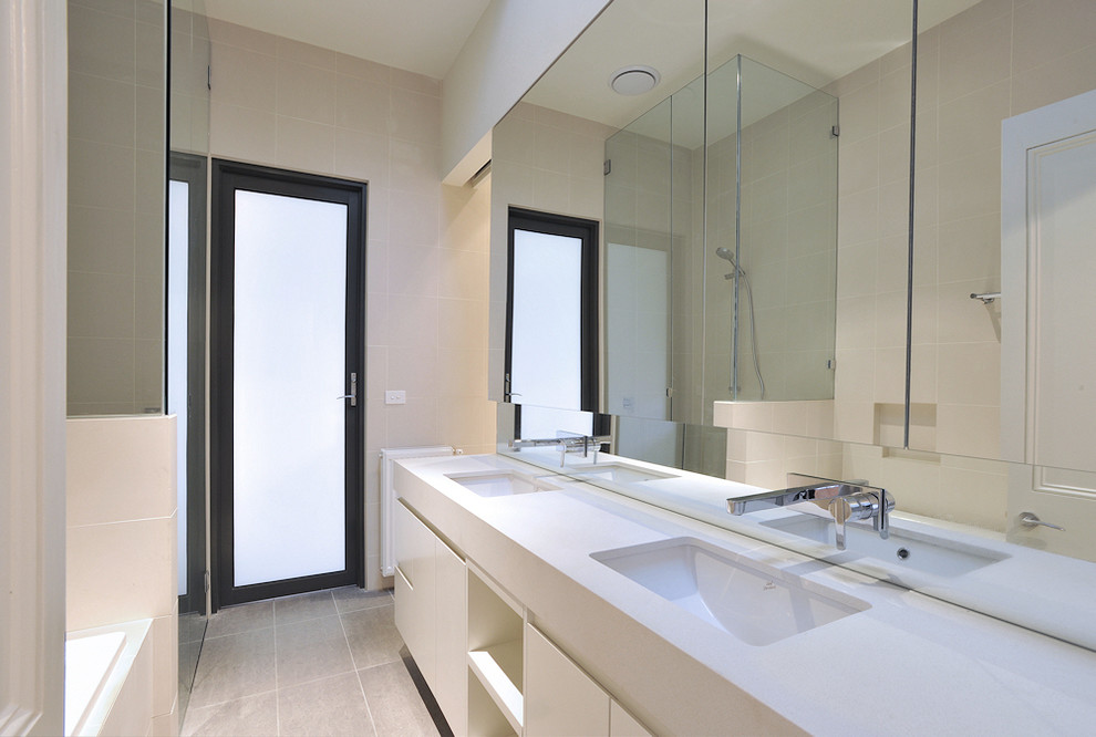 Design ideas for a mid-sized contemporary 3/4 bathroom in Melbourne with an undermount sink, engineered quartz benchtops, a corner shower, beige tile, beige walls, flat-panel cabinets, white cabinets, a drop-in tub, a one-piece toilet, ceramic tile and ceramic floors.