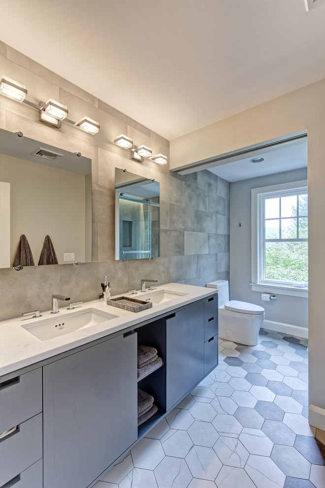 Double shower - large transitional kids' gray tile and porcelain tile ceramic tile and multicolored floor double shower idea in New York with flat-panel cabinets, gray cabinets, a one-piece toilet, gray walls, an undermount sink, quartz countertops, a hinged shower door and white countertops