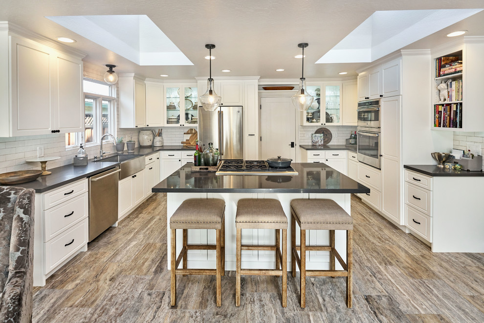 Open concept kitchen - large rustic u-shaped porcelain tile and gray floor open concept kitchen idea in San Francisco with a farmhouse sink, raised-panel cabinets, white cabinets, soapstone countertops, white backsplash, subway tile backsplash, stainless steel appliances and an island