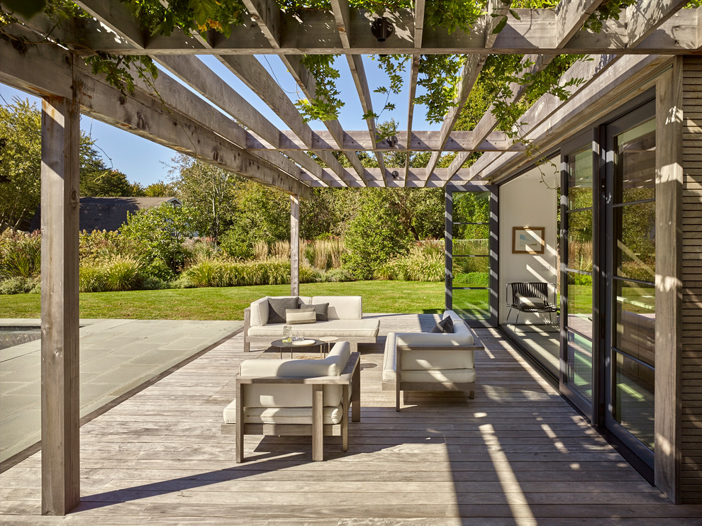This is an example of a beach style deck in New York with a pergola.