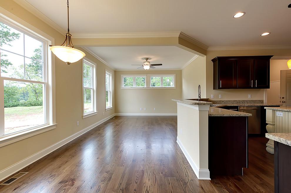 Example of a transitional u-shaped medium tone wood floor eat-in kitchen design with an undermount sink, recessed-panel cabinets, dark wood cabinets, granite countertops and an island