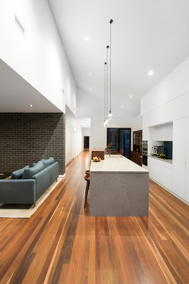 This is an example of a large contemporary single-wall open plan kitchen in Newcastle - Maitland with flat-panel cabinets, medium hardwood floors and with island.