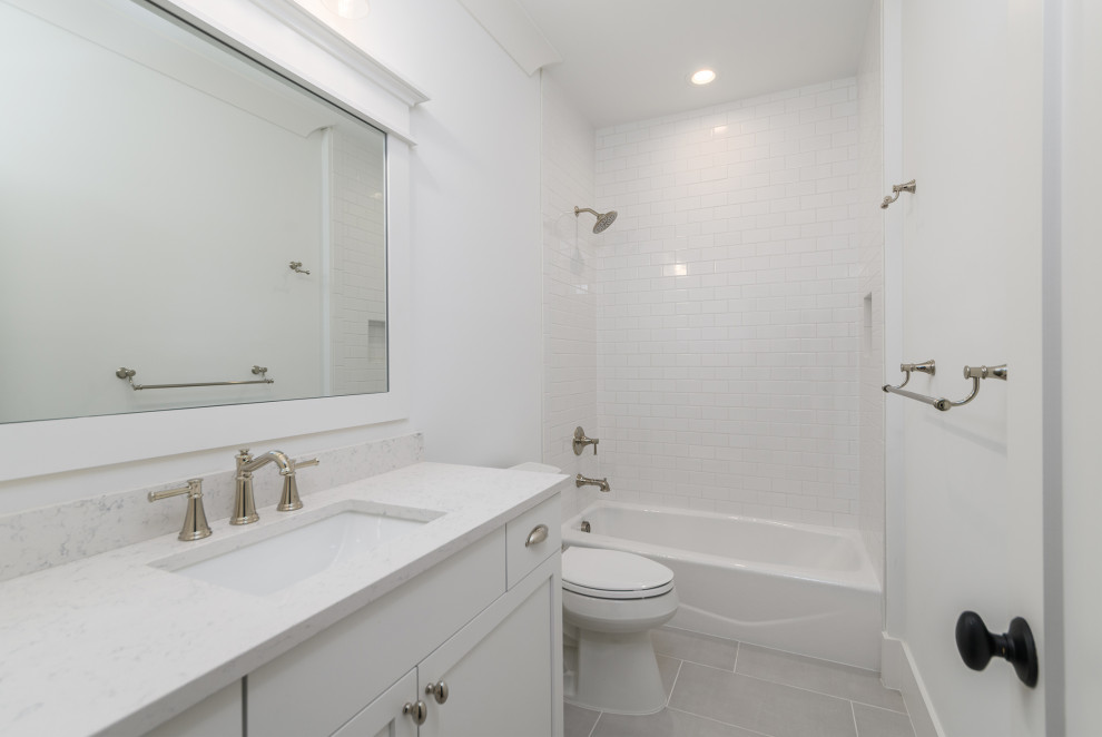 This is an example of a beach style bathroom in Other with white cabinets, a shower/bath combination, white tiles, metro tiles, white walls, a submerged sink, grey floors, a shower curtain, white worktops, a wall niche, a single sink and a built in vanity unit.