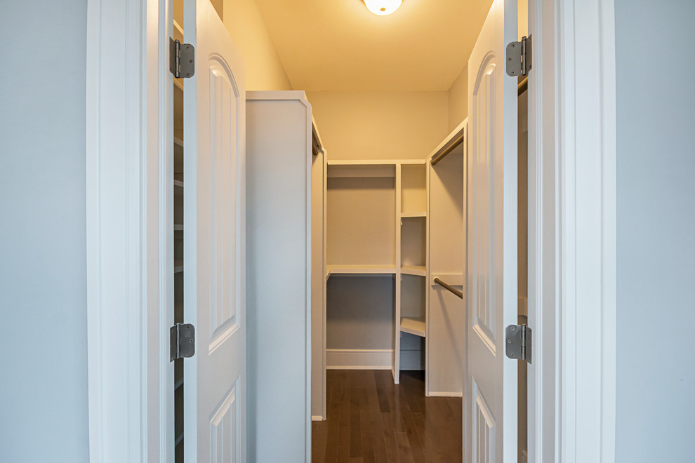 Mid-sized arts and crafts gender-neutral walk-in wardrobe in New York with white cabinets, laminate floors, brown floor and open cabinets.