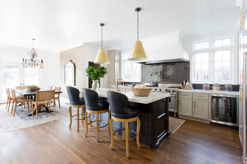 Example of a classic l-shaped dark wood floor and brown floor eat-in kitchen design in Los Angeles with shaker cabinets, gray cabinets, black backsplash, subway tile backsplash, stainless steel appliances, an island and white countertops