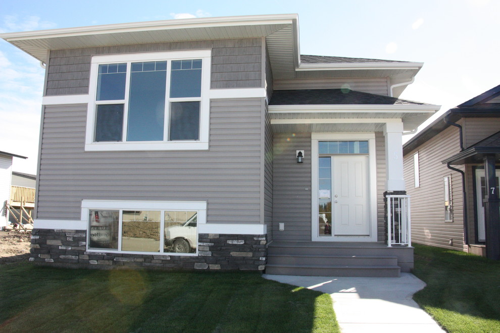 Small arts and crafts split-level grey exterior in Calgary with vinyl siding.