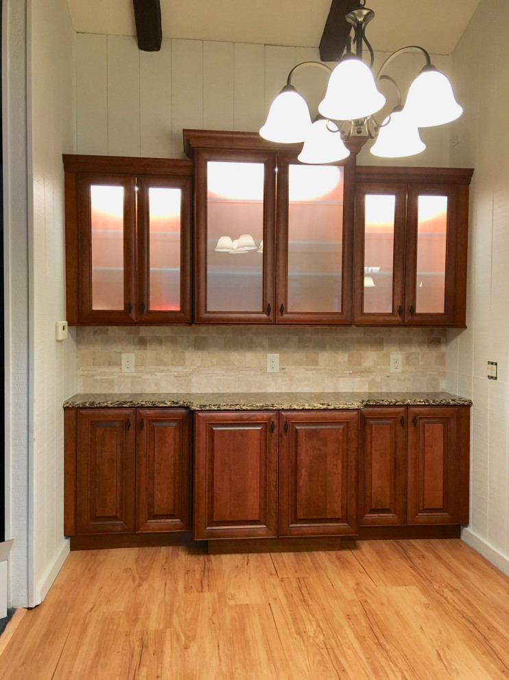 Inspiration for a large transitional l-shaped eat-in kitchen in Detroit with an undermount sink, raised-panel cabinets, medium wood cabinets, quartz benchtops, beige splashback, travertine splashback, stainless steel appliances, vinyl floors, with island, brown floor and multi-coloured benchtop.