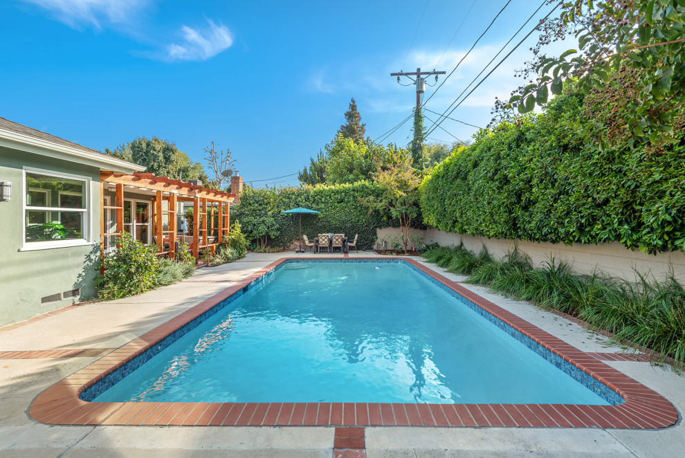 Photo of a mid-sized midcentury backyard pool in Los Angeles with concrete pavers.