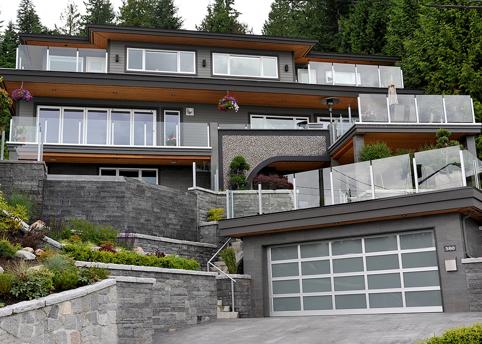 Design ideas for an expansive contemporary three-storey grey house exterior in Vancouver with mixed siding and a flat roof.