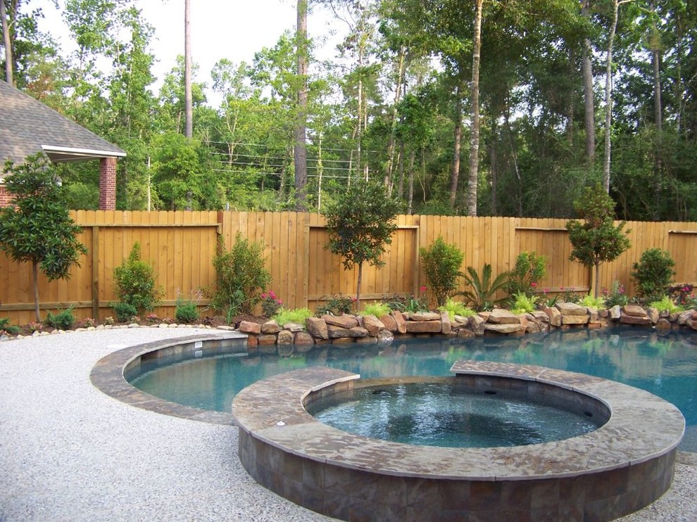 This is an example of a mid-sized traditional backyard custom-shaped pool in Houston with a hot tub and gravel.