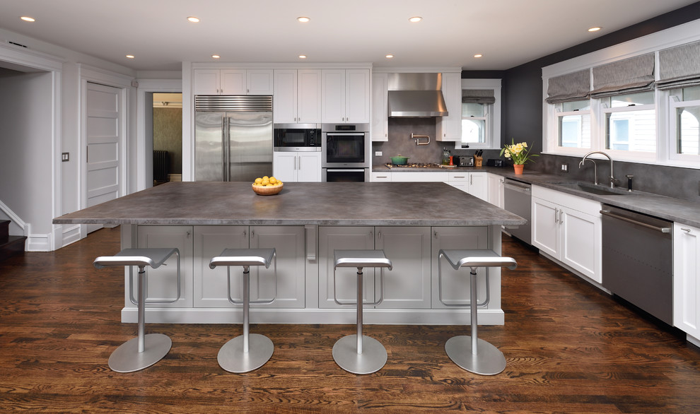 Contemporary l-shaped open plan kitchen in Chicago with an integrated sink, beaded inset cabinets, white cabinets, concrete benchtops, grey splashback, cement tile splashback, stainless steel appliances, medium hardwood floors and with island.