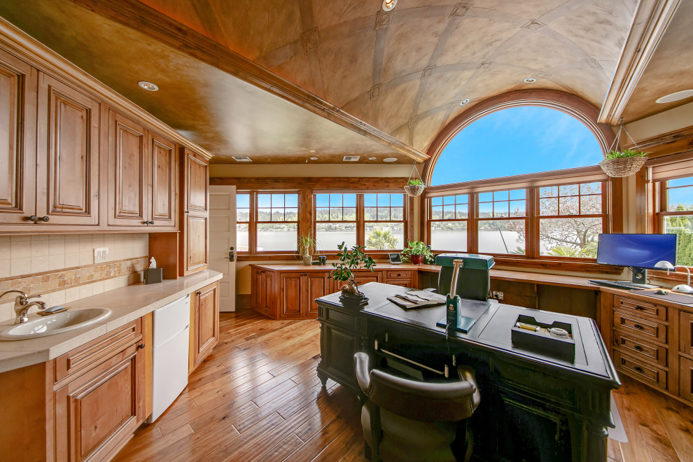 Ejemplo de despacho abovedado tradicional grande con suelo de madera en tonos medios, escritorio empotrado y madera