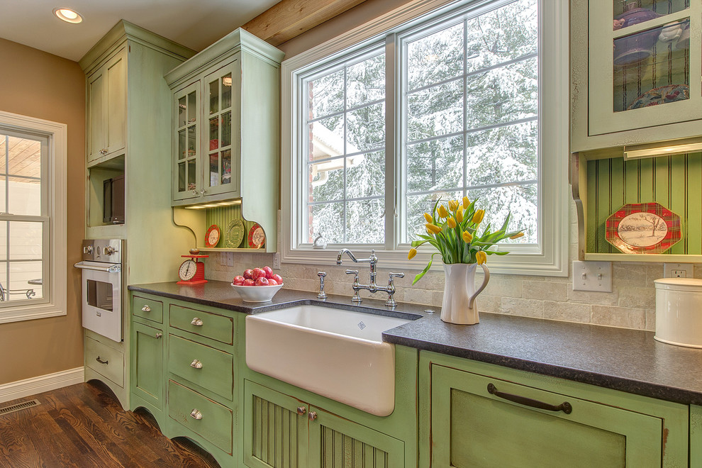 This is an example of a traditional kitchen in St Louis with white appliances, green cabinets and travertine splashback.