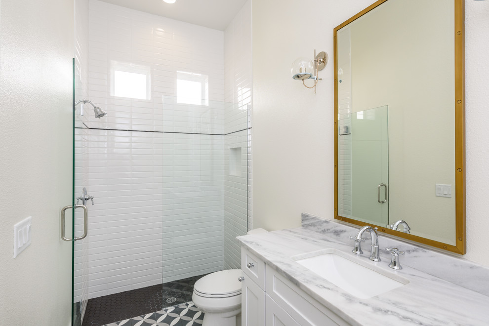 Inspiration for a mid-sized country 3/4 bathroom in Orlando with shaker cabinets, white cabinets, a curbless shower, a two-piece toilet, white tile, subway tile, white walls, mosaic tile floors, an undermount sink, marble benchtops, multi-coloured floor, a hinged shower door and multi-coloured benchtops.