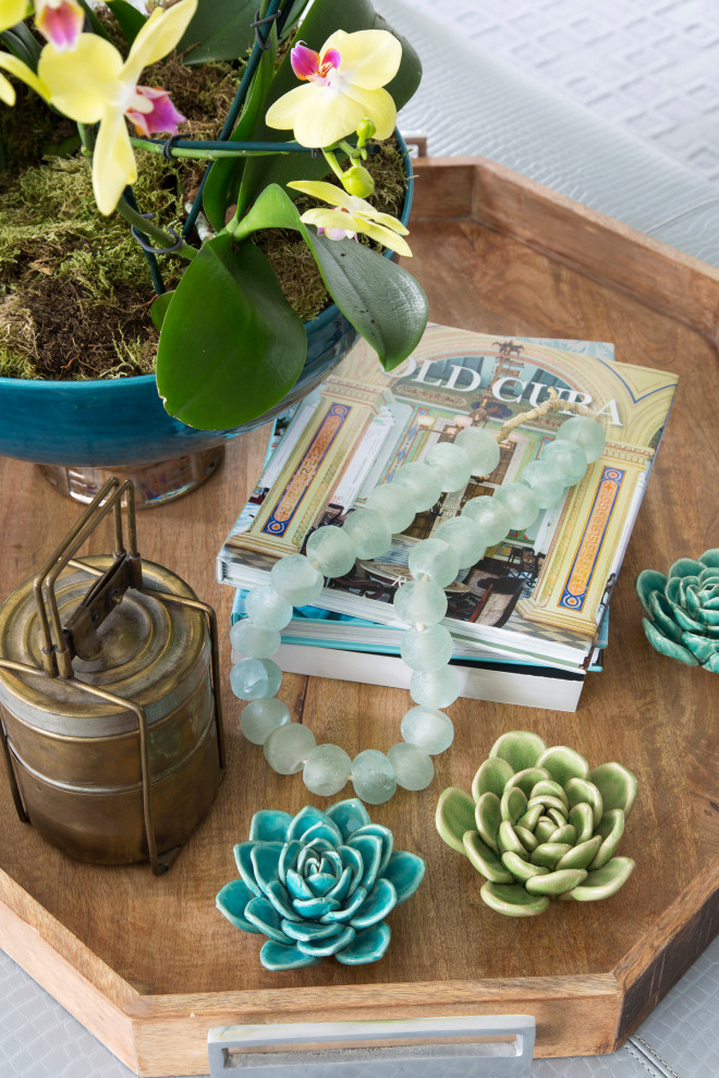 Coffee Table Styling - One of our favorite things to do is style our client's tables and ottomans with things they love.  Colorful porcelain flowers, seaglass beads, a vintage brass lunch pail, and a large planter with orchids anchor a large wooden tray on the leather cocktail ottoman.