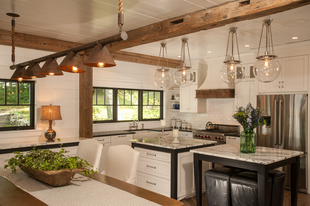 Photo of a country l-shaped eat-in kitchen in New York with a farmhouse sink, shaker cabinets, white cabinets, granite benchtops, white splashback, subway tile splashback and stainless steel appliances.