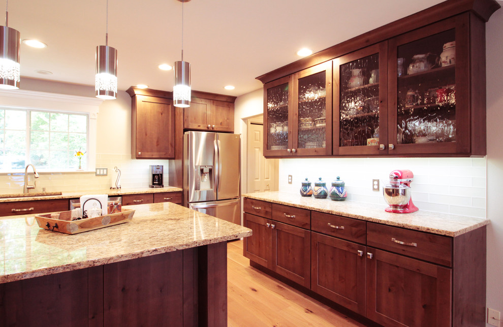 Inspiration for a large rustic u-shaped light wood floor and brown floor open concept kitchen remodel in Boise with an undermount sink, shaker cabinets, brown cabinets, granite countertops, white backsplash, glass tile backsplash, stainless steel appliances and an island