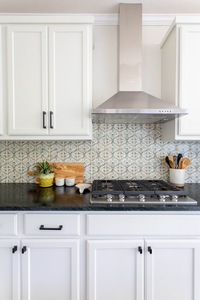 Example of a mid-sized transitional l-shaped medium tone wood floor and brown floor eat-in kitchen design in Austin with an undermount sink, shaker cabinets, white cabinets, soapstone countertops, beige backsplash, ceramic backsplash, stainless steel appliances, an island and black countertops